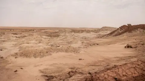 AFP/Getty Images A sandy, yellow, barren landscape beneath an orange sky.