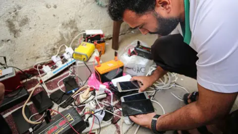 Getty Images man charging his phone in a charging station in gaza strip 