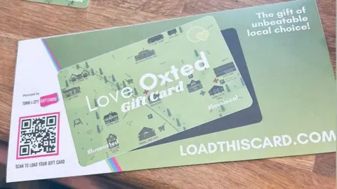 Claudia Sermbezis/BBC An image of the Love Oxted Gift Card and pamphlet laid on a table. The card is green and reads: 'Love Oxted Gift Card'.