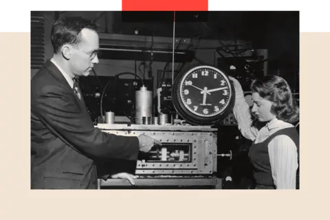 Getty Images A vintage photo from the 1950s shows Dr Charles H Townes explaining to Marianne MacDonald how the atomic clock differs from a common electric clock