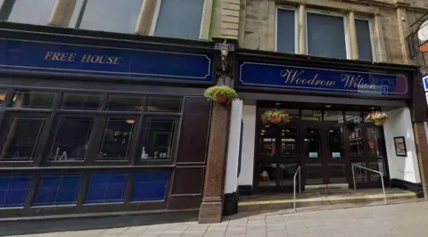 Google Image shows the outskirts of the Woodrow Wilson pub in Carlisle. It has a blue exterior with the name Woodrow Wilson written in italicised type.