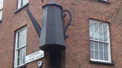 A giant 19th Century coffee pot on the side of a town building in Carmarthen town centre