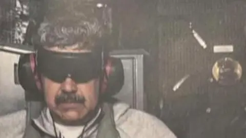 Maduro with blindfold and ear protection on the Iwo Jima