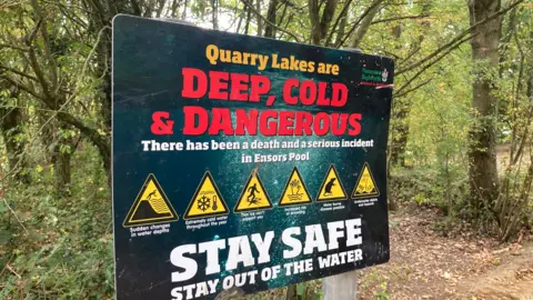A sign that says "Quarry Lakes are Deep, cold and dangerous" in orange and red bold writing.