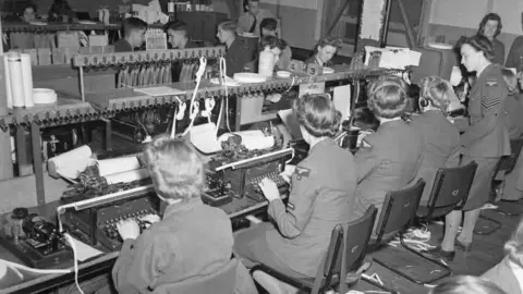 Imperial War Museum An archive black and white photo showing women wearing military uniforms set at type writers