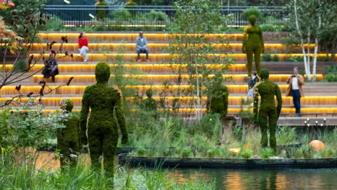 PA Media Large moss-covered statues on floating islands in the dock waters