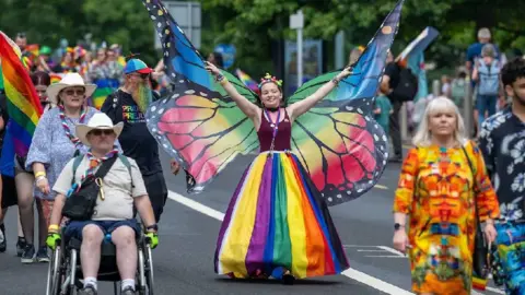 Matthew Horwood/Pride Cymru A person dressed as a buttefly, wearing a red vest top and a rainbow-coloured skirt.