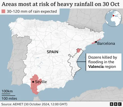 The map shows the areas most at risk of heavy rain in Spain, highlighting the cities of Barcelona and Seville. The Valencia area is also highlighted. One label said dozens of people were killed by floods in the Valencia region