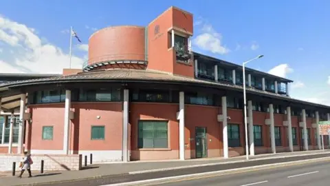 Preston Crown Court. It is an oval, red brick building with a flag on top of it.