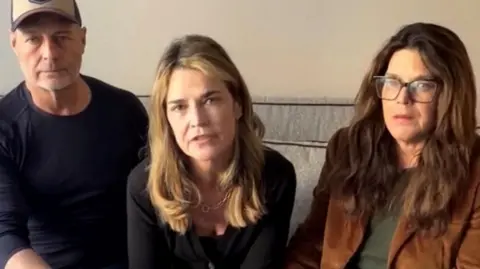 Savannah Guthrie, sitting in between two family members, addresses the camera in a video message