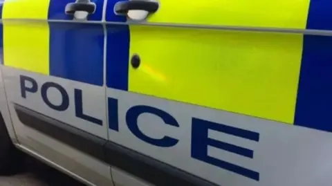 The side of a police car with police written in blue letter