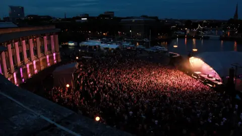 We Are Plaster A night time shot of the amphitheatre with the main stage and thousands of fans in attendance