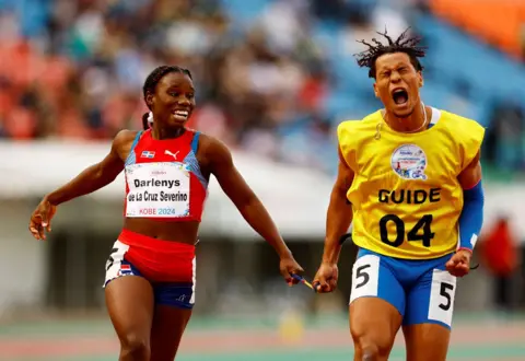 Issei Kato/REUTERS Darlenys de la Cruz Severino of Dominican Republic and her guide celebrate winning the gold medal after competing in the Women's 100m T12 final during day seven of the World Para Athletics Championships Kobe at Kobe Universiade Memorial Stadium on May 23, 2024 in Kobe, Hyogo, Japan. 