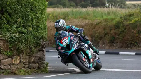 SOUTHERN 100 Michael Dunlop racing around a bend with a grass bank in the background.