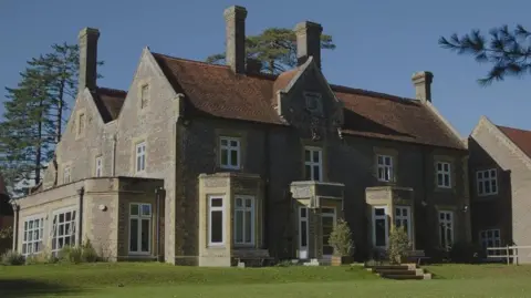 The King's School A grand old building that's now used as as a school with 6 chimneys and steps leading down to a grass lawn 