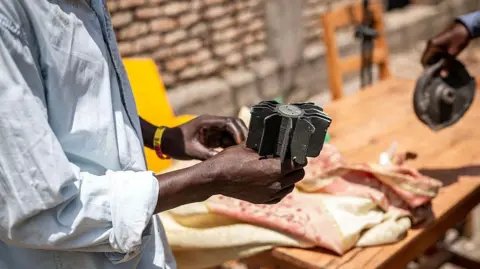 A man holds shrapnel from munitions that damaged a school following explosions after a fire at a military arsenal in the Musaga district of Bujumbura