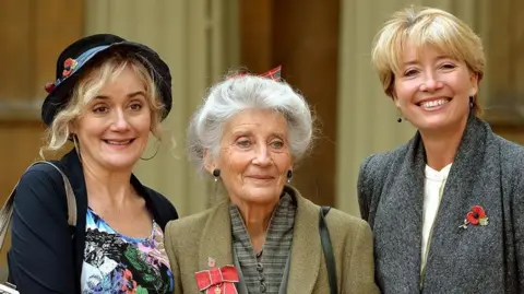 Law posing for pictures alongside her daughters Sophie (left) and Emma (right) after having been made an OBE in 2014