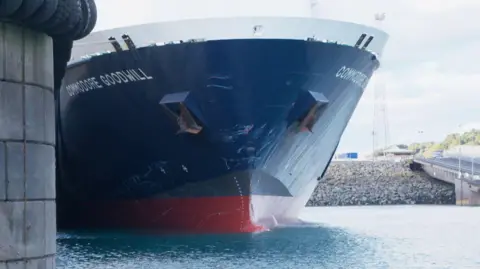 The front of the Commodore Goodwill boat coming into St Helier harbour. Clear skies behind and land.