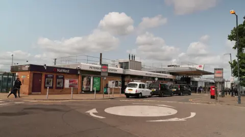 Outside of Peterborough Railway station, there is a mini roundabout and a taxi rank.