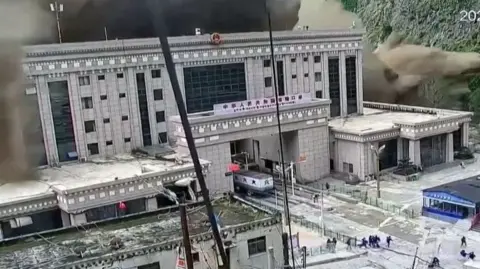 A CCTV image of a flash flood rising above a building