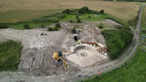 National Trust A birds eye view of volunteers using construction vehicles to excavate a World War Two gun emplacement that was hidden for 50 years