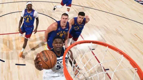 Looking down from above the basket, an image of Anthony Edwards about to score as three opponents chase him