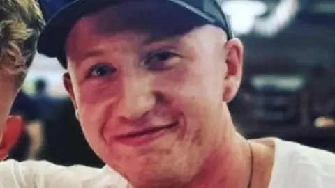 Family handout Charlie Owen is looking at the camera smiling while hugging a friend side-on. Charlie's wearing a hat and a white t-shirt.