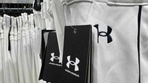 A rack of white Under Armour jogging pants in a shop