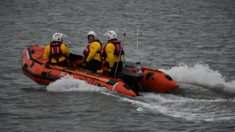 Wells RNLI Three RNLI volunteers onboard a lifeboat at sea