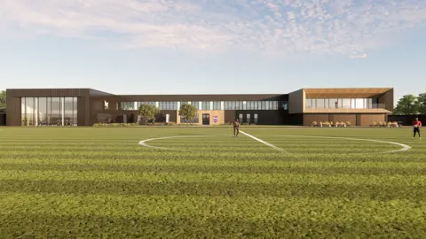 Ipswich Town Football Club Artist's impression of two-storey modern building with glass frontage to the left and glass windows on the first floor. There is a grass pitch in the foreground, with a centre circle. Two people are pictured on the pitch.