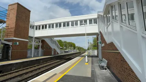 A footbridge at a small station connecting two platforms either side of the tracks.