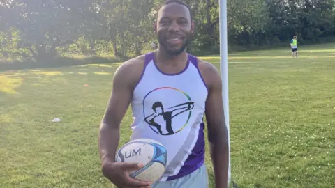 BBC/Sally Hurst Rugby player Chris Languedoc holds a rugby ball during training at West Park. He wears a purple and white Leeds Hunters tank top.