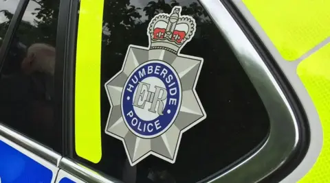 A close up of a Humberside police patrol car, with their emblem on the window.