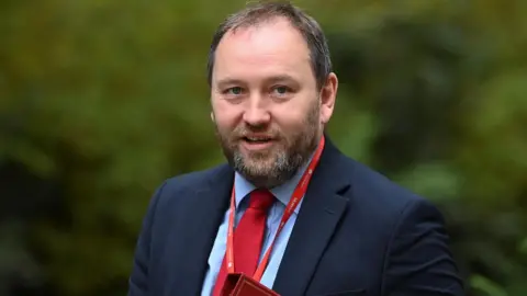 Ian Murray walking down downing street carrying a red folder