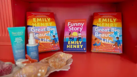 Three romance books perched against a red backdrop