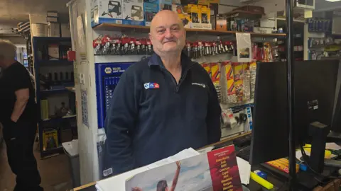 Marcus Thackray, from Wheelsbrook Services in Holmfirth, stood behind a counter wearing a dark blue jumper with the company's logo 