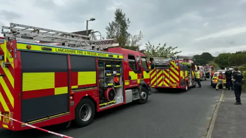 LFRS Fire vehicles behind emergency service tape as workers attend the scene on Wheatley Drive 