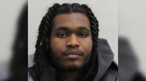 Met Police Awad Abdel Samad is seen close up in a police mugshot. He is seen wearing a grey hoodie.