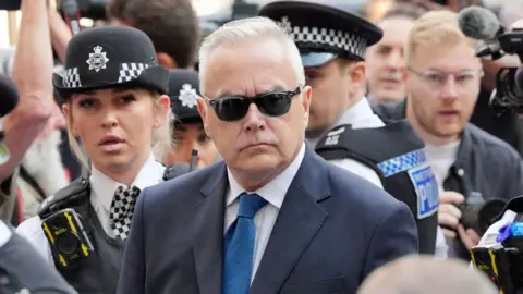 PA Media Huw Edwards cercado pela polícia do lado de fora do tribunal