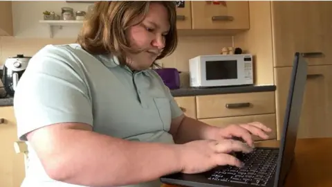 BBC Kye Vallance sits at his laptop typing from his kitchen
