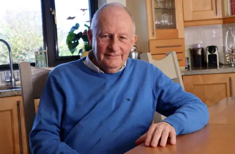 BBC / Steve Swann  Safeguarding expert Ian Elliott, wearing a blue pullover, seated at a kitchen table 