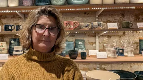 Mel Condon standing in front of pottery 