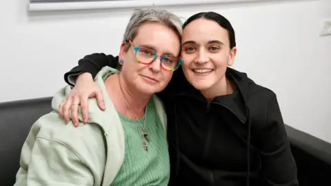 Emily (right) and her mother Mandy (left) sit with their arms around each other