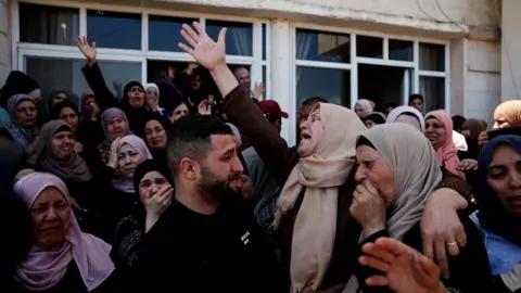Mourners react during the funeral of Palestinian men who were killed during an attack by Israeli settlers in Kafr Malik, in the Israeli-occupied West Bank (25 June 2025)
