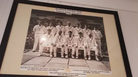 A black and white image of cricket players in a team photo with their hands on their knees and their names in captions below.