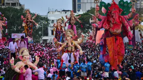 Hindustan Times via Getty Images Devotees carry an idol of the Hindu deity Ganesha for immersion at Girgaon Chowpatty during 'Ganesh Chaturthi' festival, on September 6, 2025 in Mumbai, India. 