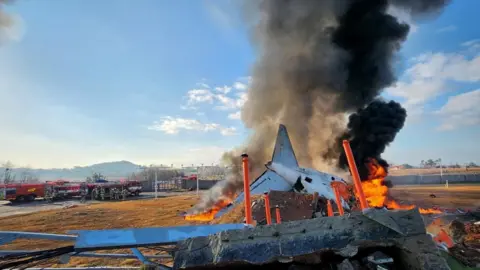 Reuters Smoke and flames erupt from the aircraft as firefighters carry out extinguishing operations. 