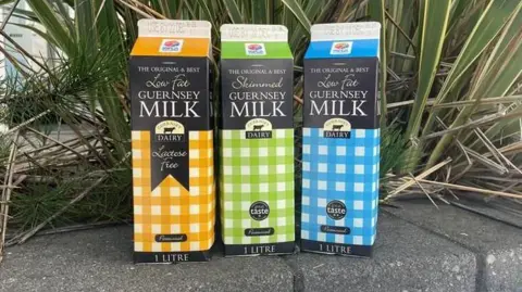 BBC Yellow, blue and green Guernsey milk cartons on a wall.