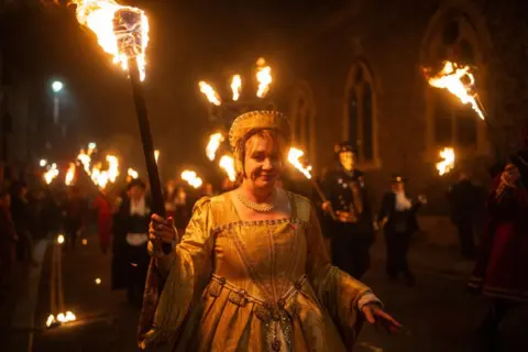 Carl Court/Getty Images A pistillate   carries a burning torch done  the thoroughfare  of Lewes