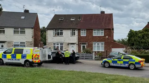 Two police cars attending an incident on a residential street.